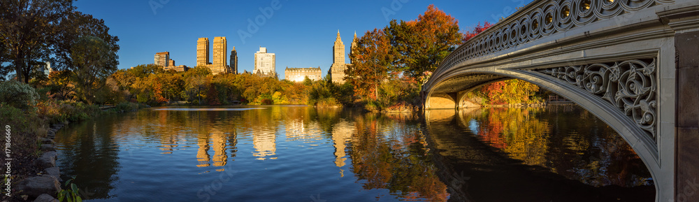 Fall in Central Park at The Lake with the Bow Bridge. Panoramic morning view with colorful autumn foliage on the Upper West Side. Manhattan, New York City