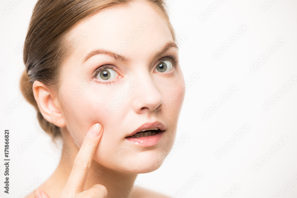 Young caucasian woman who checks her skin. Pimple treatment concept.