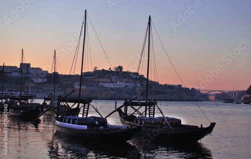 sailing boats loaded with barrels stand in a small port at sunse