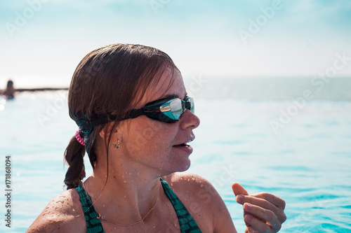Portrait of a smiling woman in a swim glasses in a pool