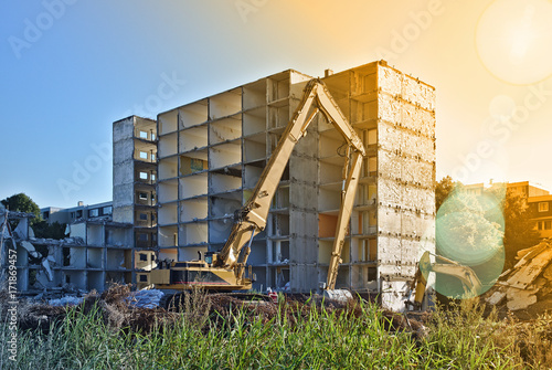 Demolished residential building being torn down by two excavators