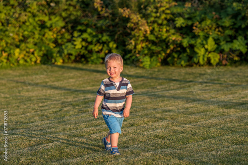 One year old baby boy running on meadow