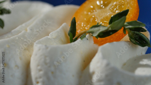 Kumquat on the cream. Orange kumquat is located on the white cream close up photo