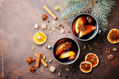 Two cups of christmas mulled wine or gluhwein with spices and orange slices on rustic table top view. Traditional drink on winter holiday.