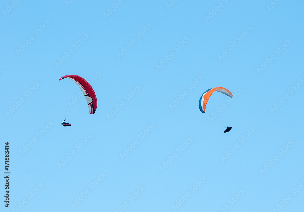 Two paragliders flying in the blue sky. Paragliding in the sky on a sunny summer day. Two paragliders flying in the blue sky. Paragliding in the sky on a sunny summer day.
