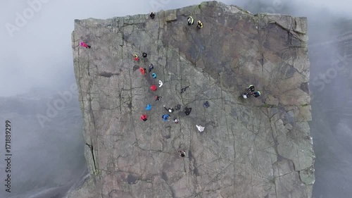 Aerial shot tourist attraction in Norway. Tourists walk on a large rock. Preikestolen Landscape, Prekestolen, Preacher's Pulpit or Pulpit Rock. Magnificent scenery, mountains, steep cliffs in the fog