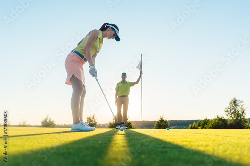Frau auf dem Golfplatz übt Putting mit dem Golf Lehrer photo