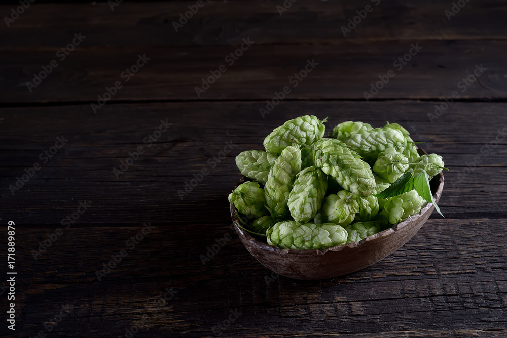 cones of hops in a wooden bowl on a wooden background cones of hops in a wooden bowl on a wooden background