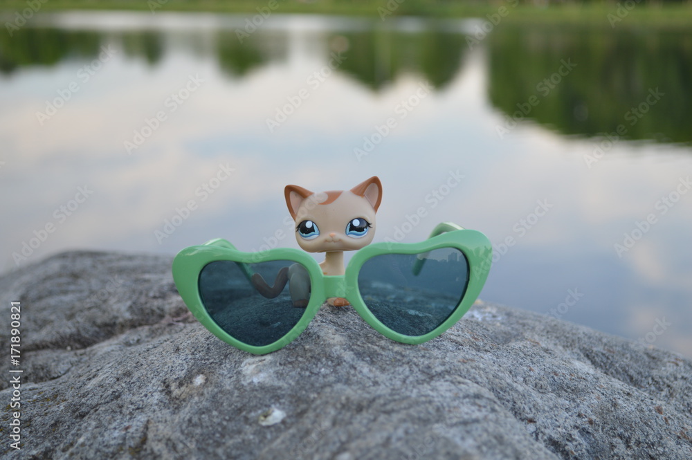 Toy cat with sunglasses on the beach