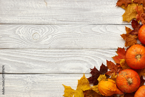 Autumn leaves and pumpkins over old wooden background