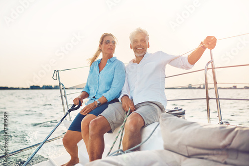 Smiling couple sailing their boat together on a sunny afternoon