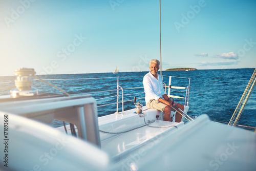 Mature man sitting on his boat out at sea © Flamingo Images