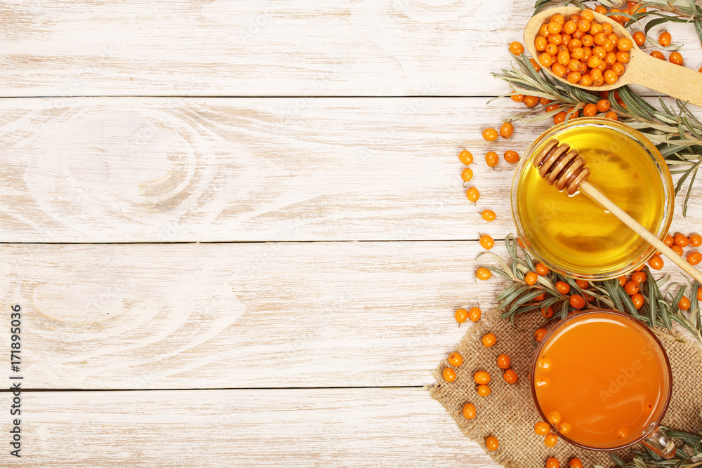 Sea buckthorn juice or tea with honey on a white wooden background with copy space for your text. Top view Sea buckthorn juice or tea with honey on a white wooden background with copy space for your text. Top view