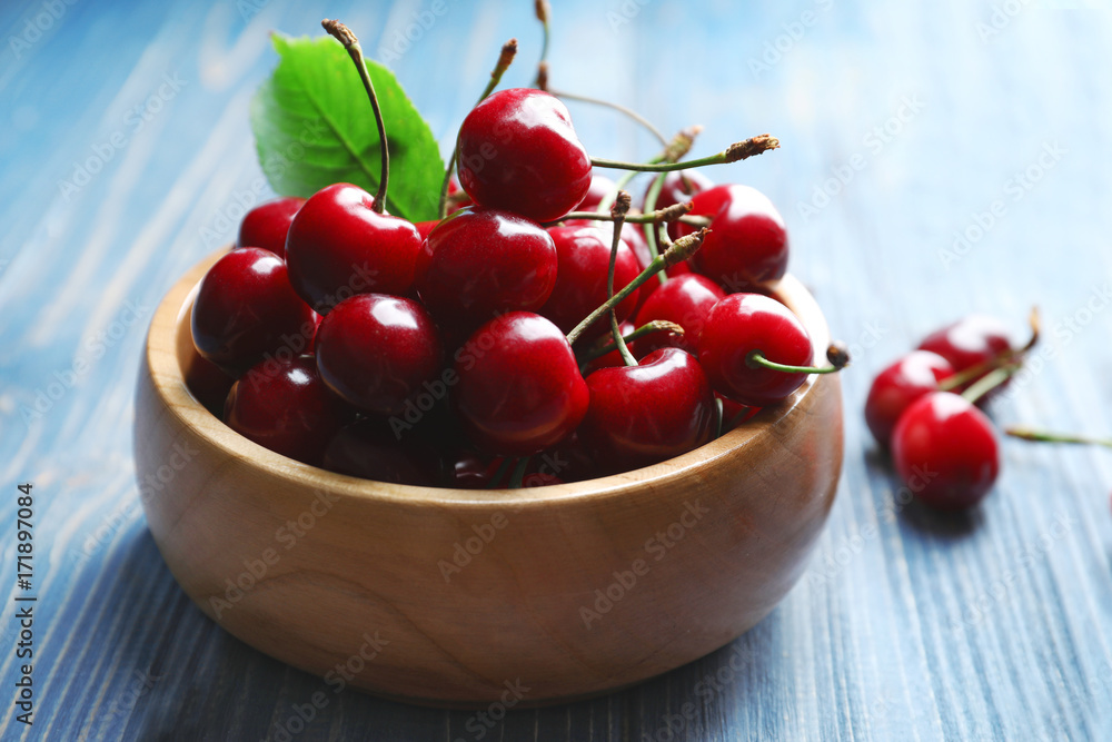 Bowl with tasty ripe cherries on wooden table