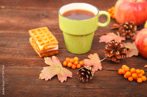 Fototapeta Naklejka Na Ścianę i Meble -  autumn composition. still life. berries of mountain ash, pine cones, fallen leaves and a cup of tea on a background of wood.