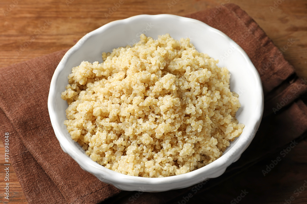 Bowl with boiled white quinoa grains on wooden table Bowl with boiled white quinoa grains on wooden table