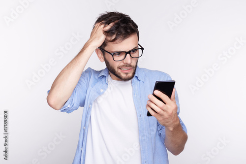 Handsome European blue eyed guy received provocative video from last night birthday party. Confused and surprised young bearded Caucasian hipster trying to remember name of lady who is calling him.