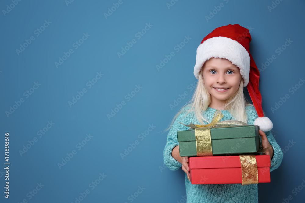 Cute little girl with Christmas present on color background