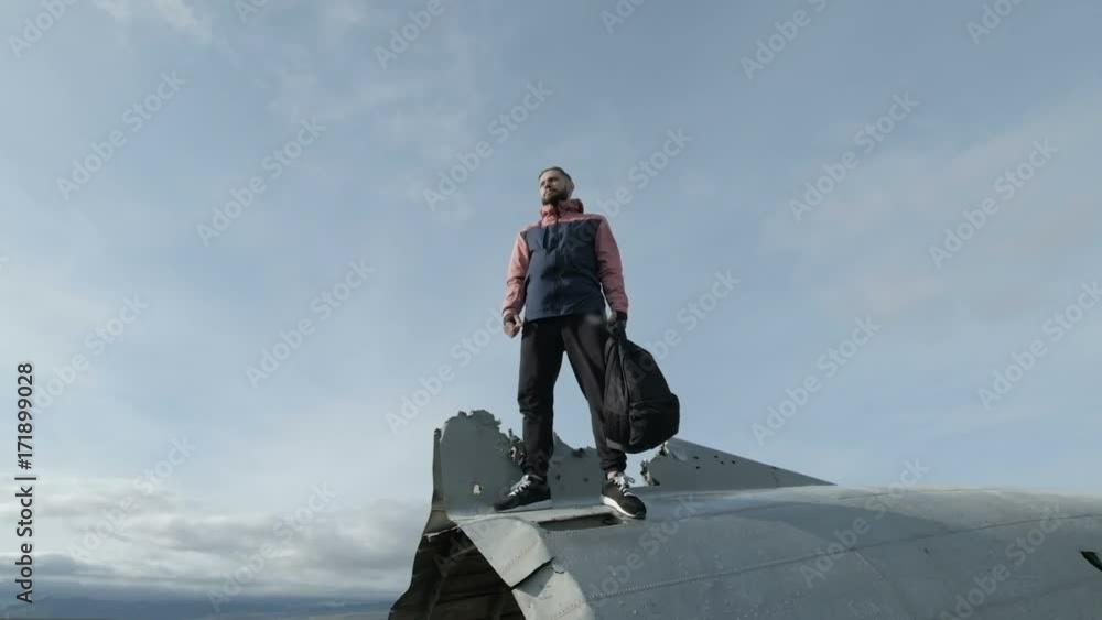 Walking man on the old crashed plane abandoned on Solheimasandur beach near Vik in Iceland Walking man on the old crashed plane abandoned on Solheimasandur beach near Vik in Iceland