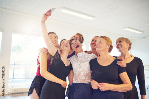 Fototapeta Naklejka Na Ścianę i Meble -  Group of laughing women taking selfies in a dance studio