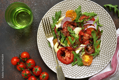 Colorful tomato salad "Caprese"with arugula and mozzarella cheese.Top view with copy space.