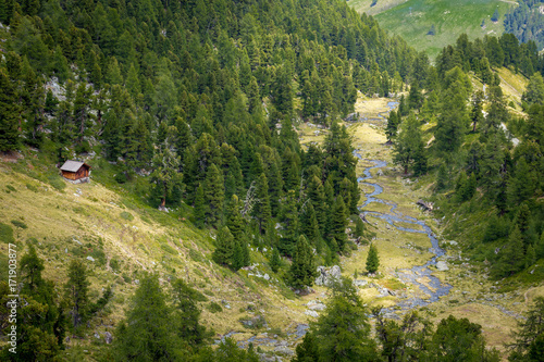 vue aérienne sur un paysage de montagne avec un chalet surplombant une rivière au milieu des bois