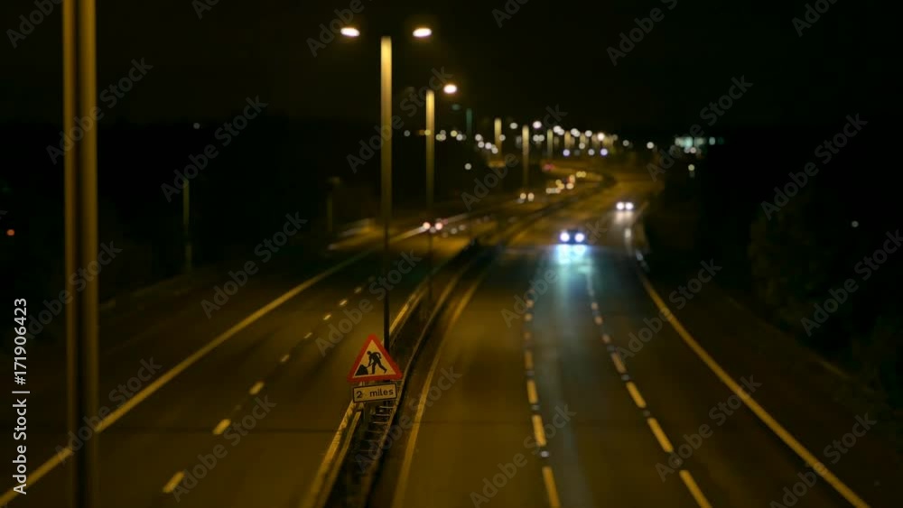 Roadworks signage on a UK motorway in Birmingham at night. Cars passing in soft focus. Roadworks signage on a UK motorway in Birmingham at night. Cars passing in soft focus.