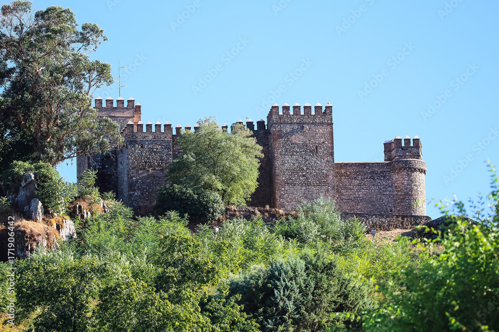 Castle wall with battlement and fortified tower in clear and sunny autumn day in a village named 