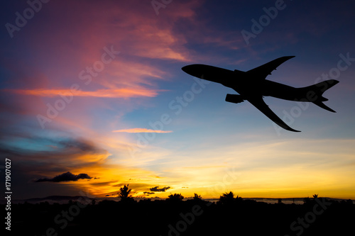 Silhouette airplane taking off flight with blue and red sky background
