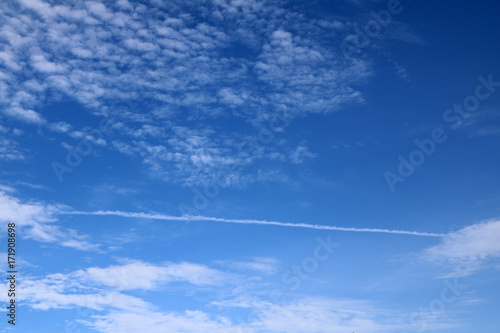 The white cloud and the line of Jet plane engine exhaust contrails forming on the blue sky. The beauty of clouds and the blue sky According to the imagination.