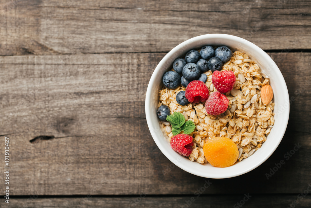 Homemade granola with dried fruit and berries on wooden background Homemade granola with dried fruit and berries on wooden background