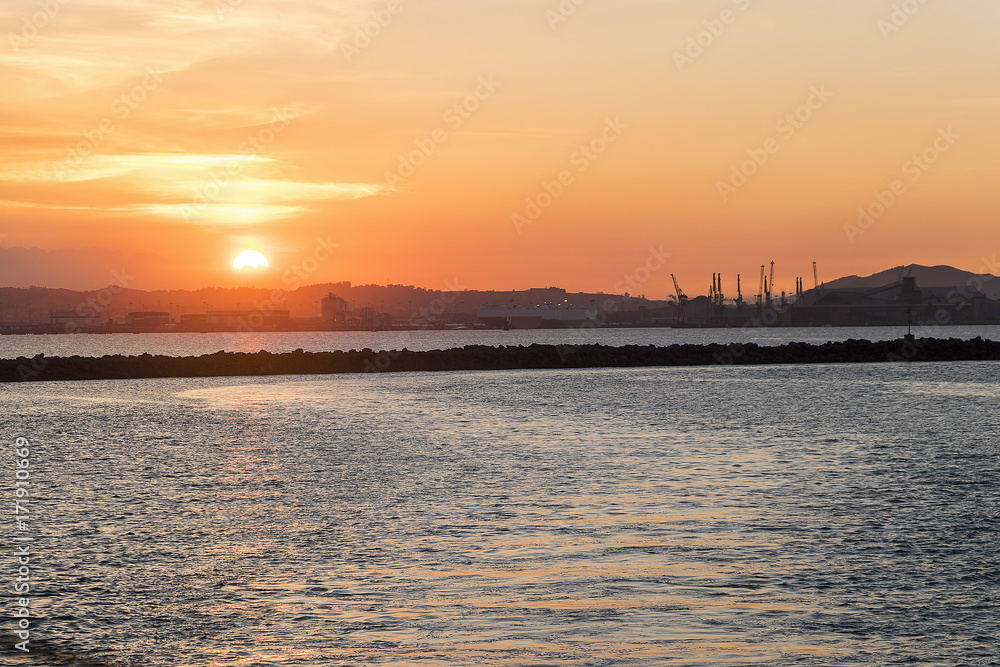 Panoramic view of silhouette of Santander harbor and shipyard, from the Bay of Santander at sunset. Cantabria, Spain