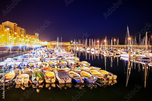 SANTANDER, SPAIN - February 20, 2017: Pier with many moored boats in the port at night photo
