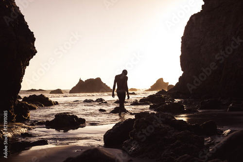 man walking with head down at beach