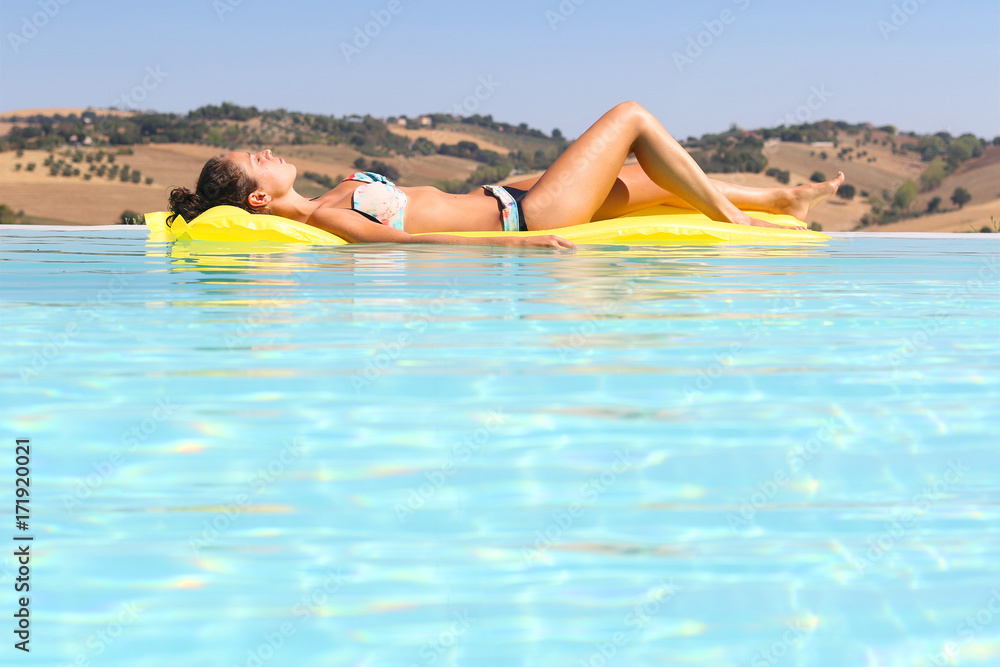 Young woman relaxing on air mattress in a pool