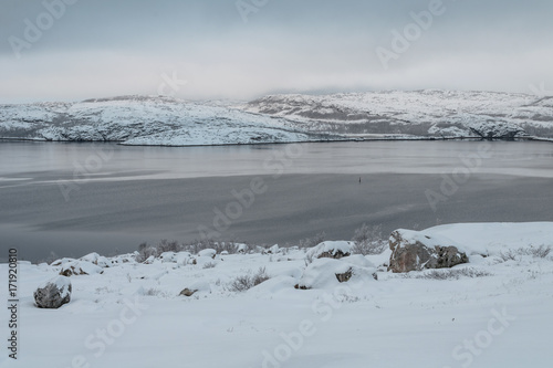 The snow on the hills and the shores of the bay in winter .