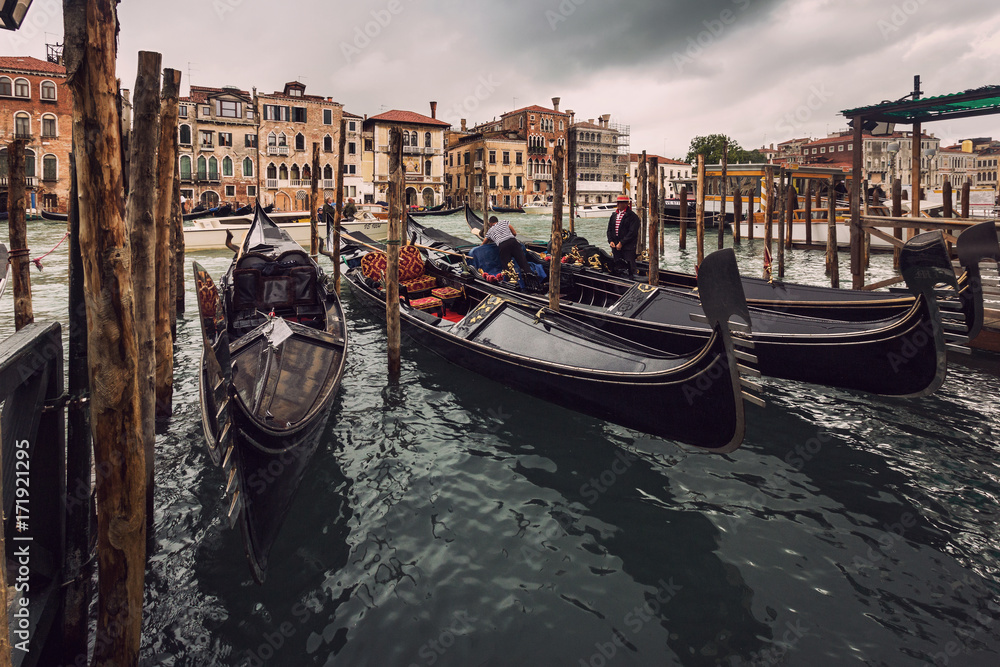 Moored gondolas around a wooden pier in a rainy day in Venice