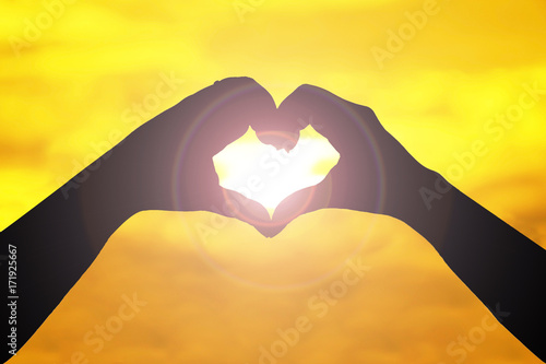 Silhouette hand with Heart shape gesture on sunset background