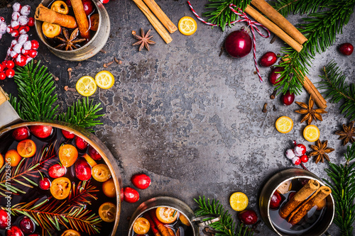 Christmas Mulled wine cooking preparation with pot, cups , ingredients and festive decorations on dark rustic background, top view, frame. Christmas food concept