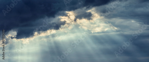 Beautiful dark storm cloudy sky with rays of the sun breaking through the clouds © VICUSCHKA