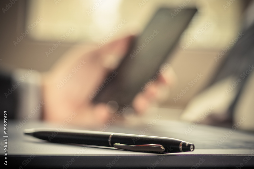 Fototapeta premium Selective focus pens lies in laptop keyboard on background businessman using a mobile phone blurry