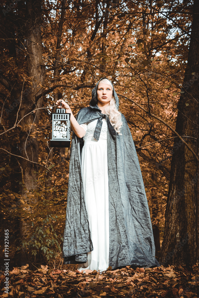 Woman with black coat and a lantern in a forest Woman with black coat and a lantern in a forest