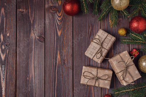 Christmas gift boxes and fir tree on wooden background.