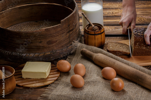 The hand cuts black bread on the background of ingredients for cooking bread photo