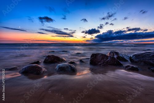 Baltic Sea sunset seascape with wet rocks. Smooth long exposure of waves