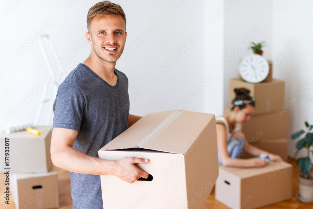 Moving day. Young man carrying cardboard box and smiling. Moving day. Young man carrying cardboard box and smiling.