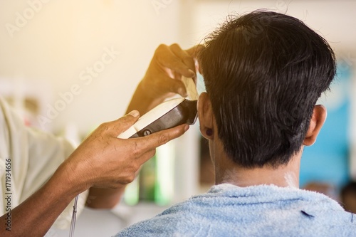 The man is being cut by a hairdresser in the barber.