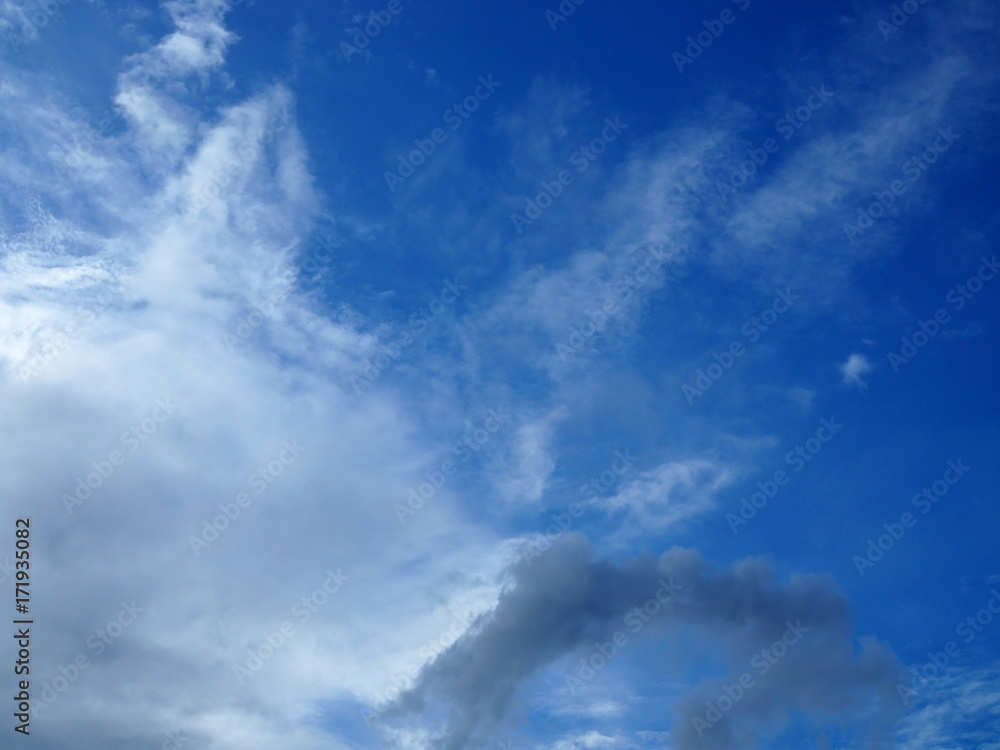 Bright clear gradient blue sky background with gradient chunk of white grey dark cloud from lower left corner