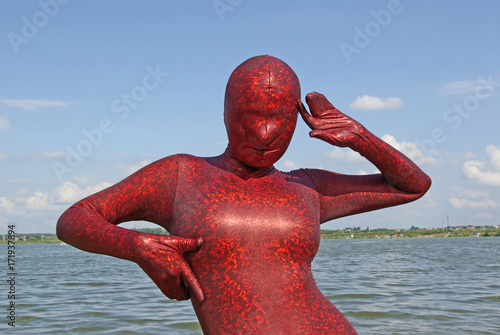 beautiful curvy woman wearing red spandex fetish zentai costume on the beach photo