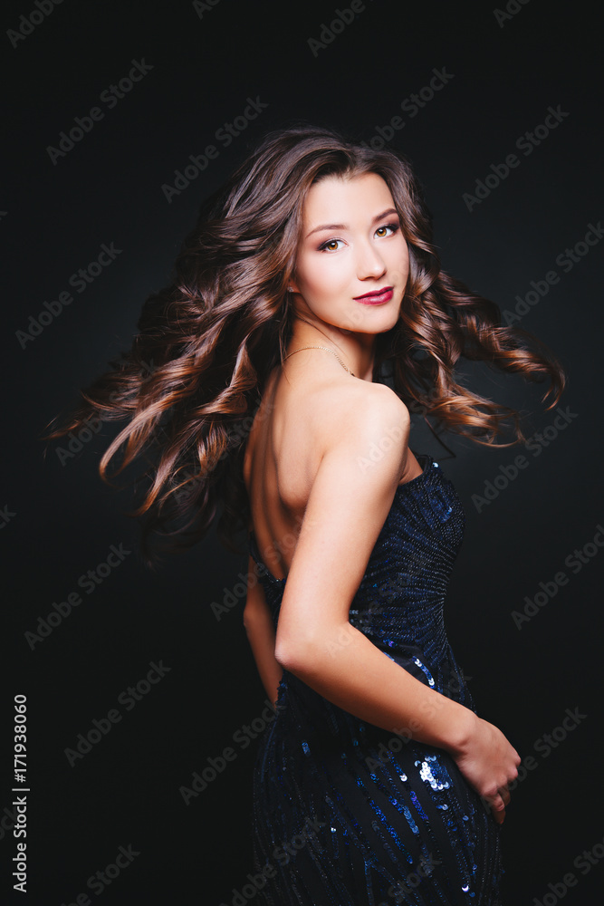 Naklejka premium Flying curly hairs. Woman with perfect make-up in dress glitters. Celebration